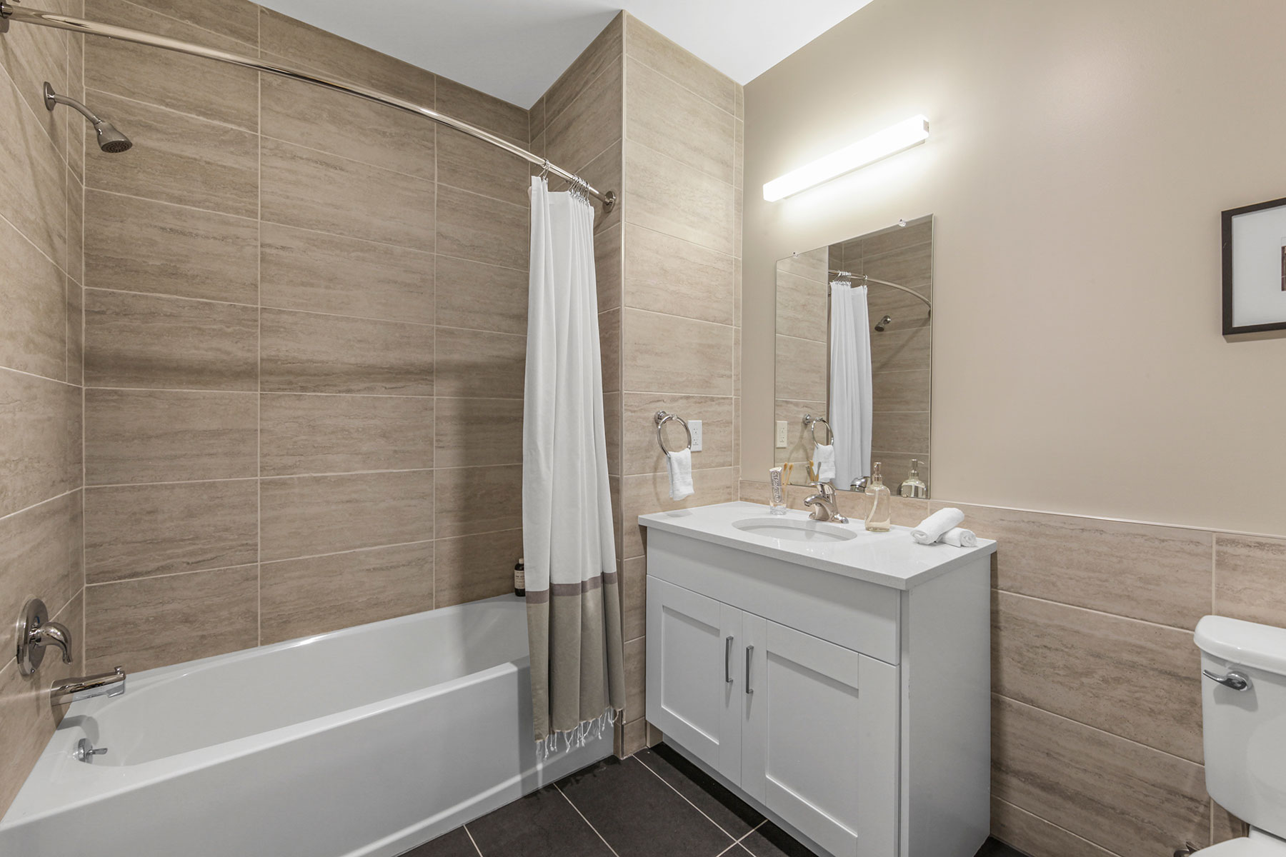 Modern bathroom with double cabinet white vanity, fully tiled tub shower, tiled floor and tiling halfway up wall